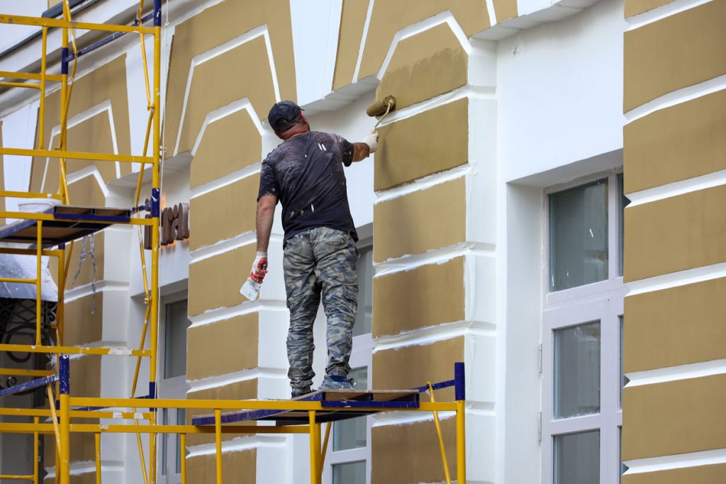 Maler streicht Fassade in Herne gelb an